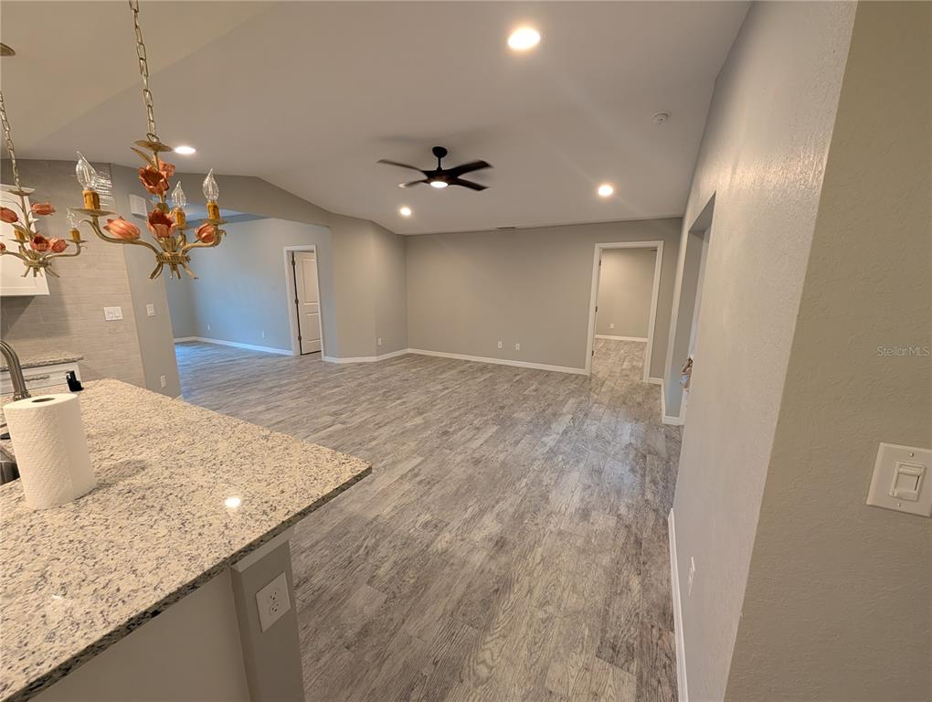 An open-concept living area features light gray walls, wood-look flooring, and a granite kitchen island — 12190 KNEELAND TERRACE, PORT CHARLOTTE, FL