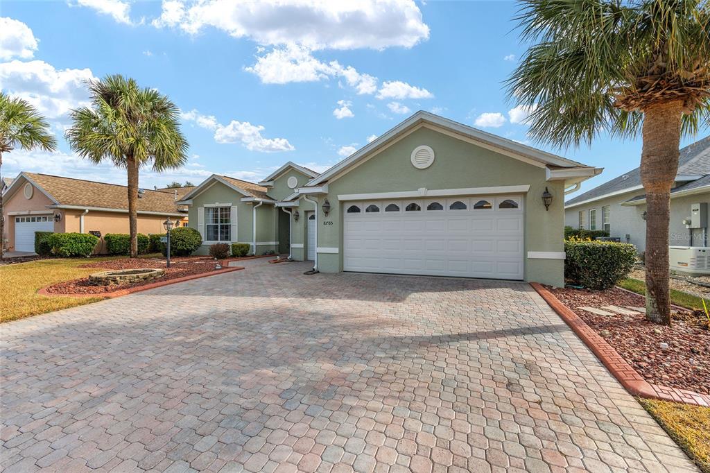 A light green single-story house features a paved driveway, a two-car garage, and palm trees — 8785 SW 82ND COURT ROAD, OCALA, FL