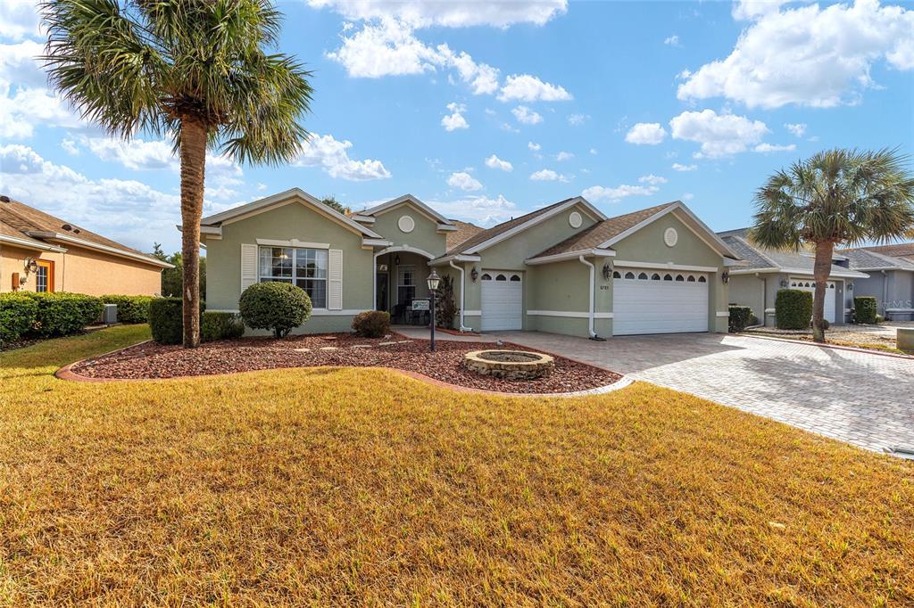 A single-story house with a light green exterior, a two-car garage, and a palm tree — 8785 SW 82ND COURT ROAD, OCALA, FL