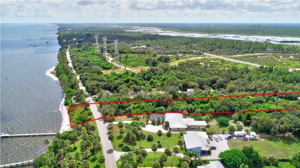 An aerial view shows a waterfront property with a house, pool, and surrounding wooded area — 7507 S Indian River Dr, Fort Pierce FL 34982, FORT PIERCE, FL