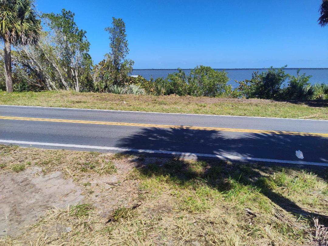 A paved road runs alongside a grassy area with trees overlooking a body of water — 7507 S Indian River Dr, Fort Pierce FL 34982, FORT PIERCE, FL
