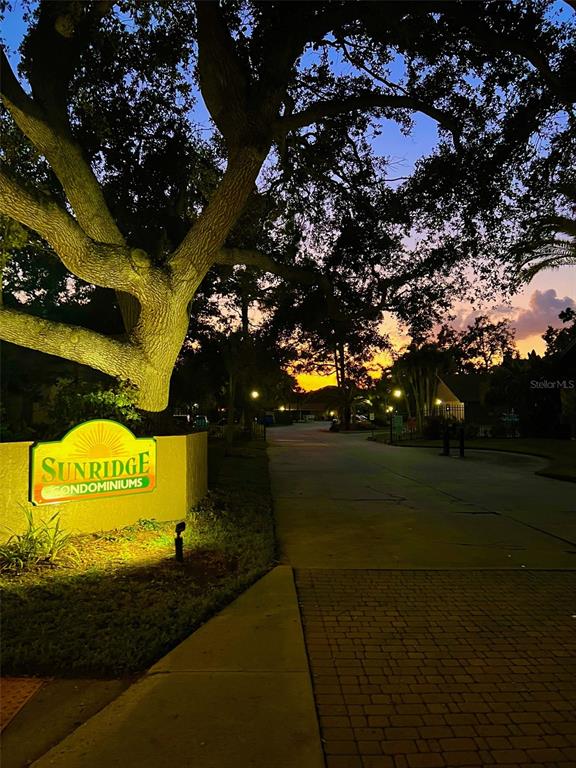 A Sunridge Condominiums sign stands under a large tree at the entrance during sunset — 984 SUNRIDGE DRIVE UNIT J3, SARASOTA, FL