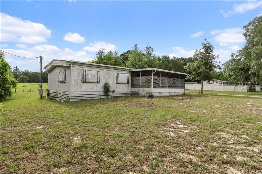 A single-story mobile home with a screened-in porch sits on a grassy lot — 8415 S LINDEN POINT, FLORAL CITY, FL
