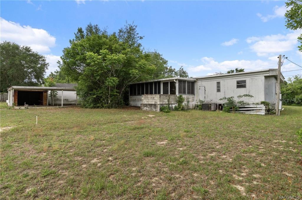 A mobile home with a screened porch and a detached garage sits on a grassy lot — 8415 S LINDEN POINT, FLORAL CITY, FL