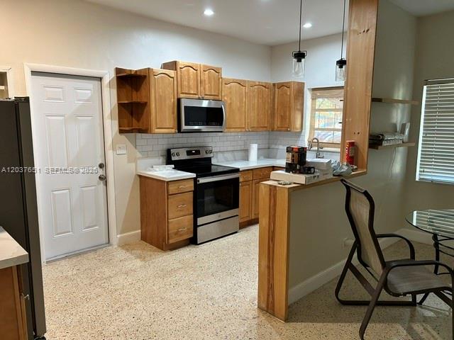 A kitchen features light wood cabinets, stainless steel appliances, and a speckled terrazzo floor — BOYNTON BEACH, FL