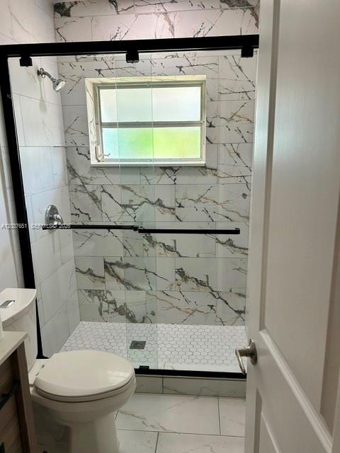 A bathroom features a walk-in shower with marble-patterned tiles, a glass door, and a toilet — BOYNTON BEACH, FL