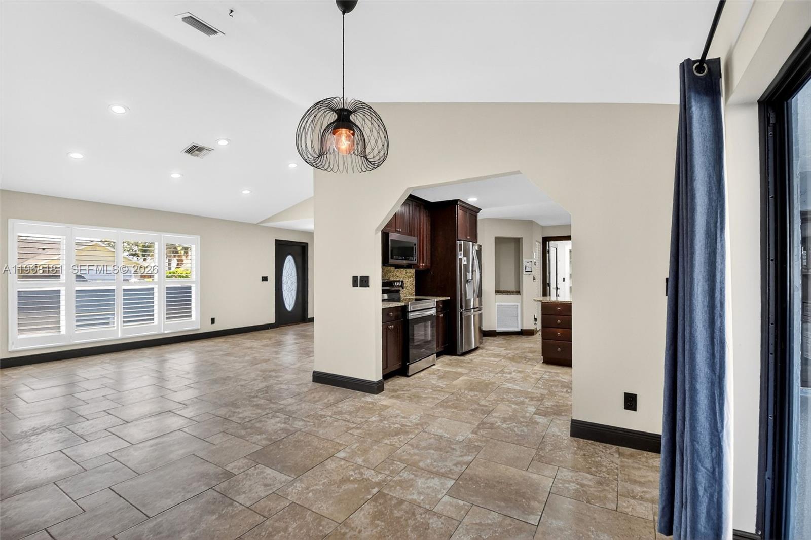 An open-concept living area features tile flooring, a modern pendant light, and a dark kitchen — 13808 Geranium Pl, Wellington FL 33414, WELLINGTON, FL