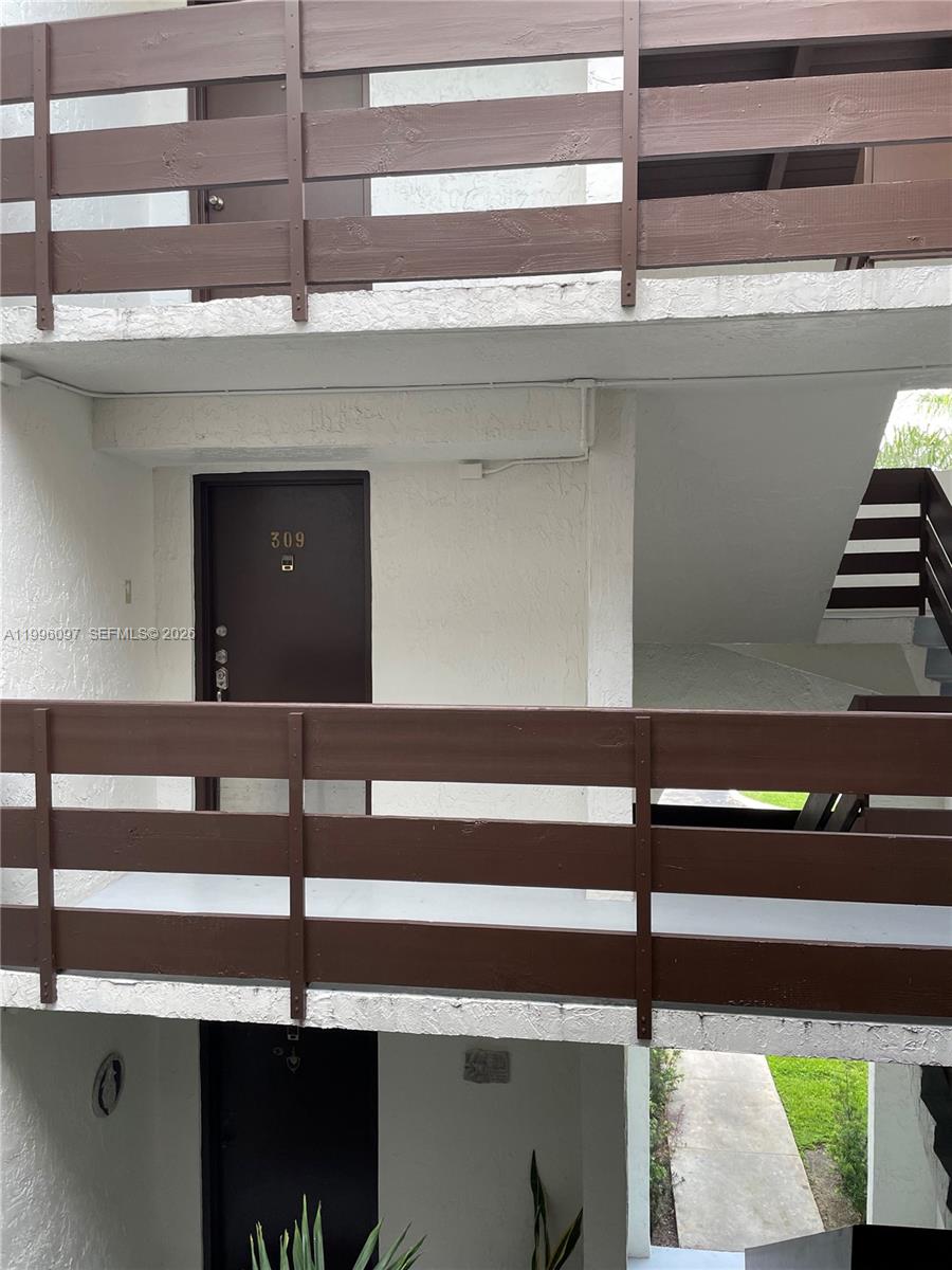 An exterior view shows a multi-story apartment building with brown wooden railings and staircases — 9140 SW 123rd Ct # 309, Miami FL 33186, MIAMI, FL