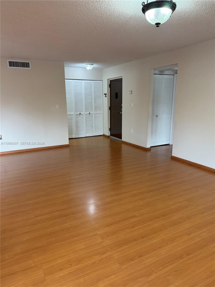 An empty room features wood-look flooring, white walls, and two sets of white louvered closet doors — 9140 SW 123rd Ct # 309, Miami FL 33186, MIAMI, FL