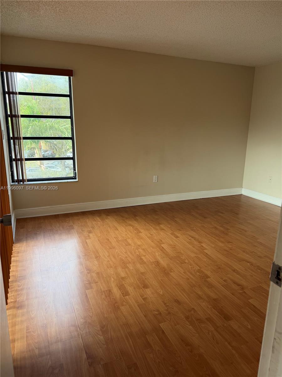 An empty room features light wood-look flooring, beige walls, and a window with blinds — 9140 SW 123rd Ct # 309, Miami FL 33186, MIAMI, FL