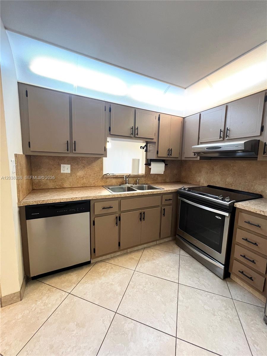 A kitchen features brown cabinets, stainless steel appliances, tan countertops, and light-colored tile flooring — 12035 NE 2nd Ave # A302, North Miami FL 33161, NORTH MIAMI, FL