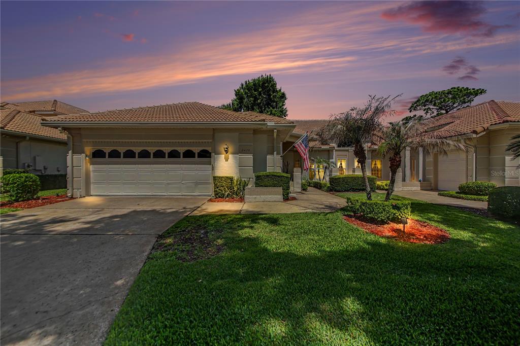 A single-story house with a tile roof, two-car garage, and a landscaped front yard — 2406 SWEETWATER COUNTRY CLUB DRIVE, APOPKA, FL