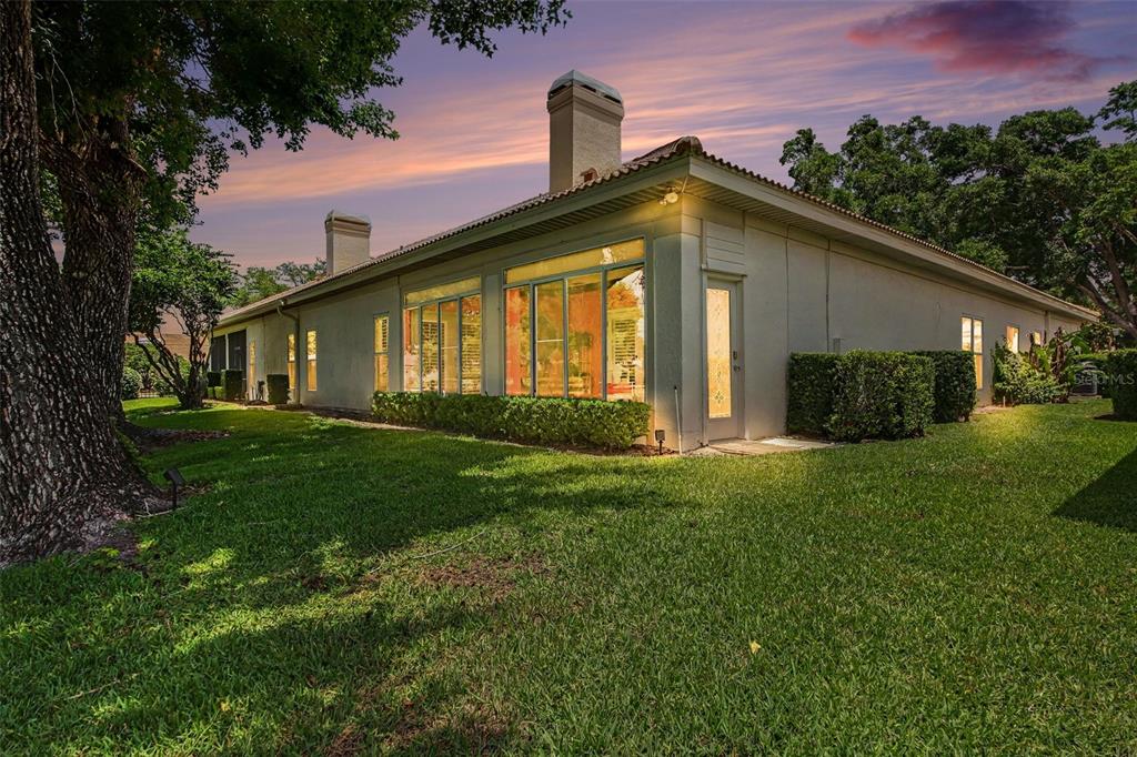 The exterior of a single-story house features a light-colored stucco facade and large windows — 2406 SWEETWATER COUNTRY CLUB DRIVE, APOPKA, FL