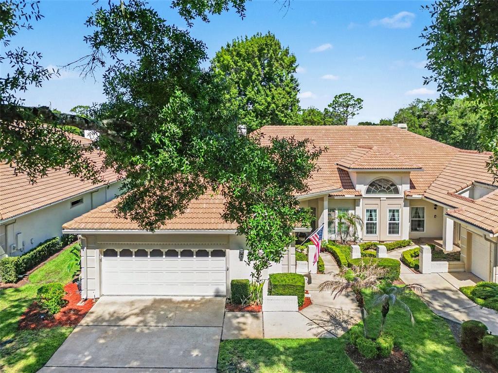 An aerial view of a single-story house with a tile roof, garage, and landscaped yard — 2406 SWEETWATER COUNTRY CLUB DRIVE, APOPKA, FL