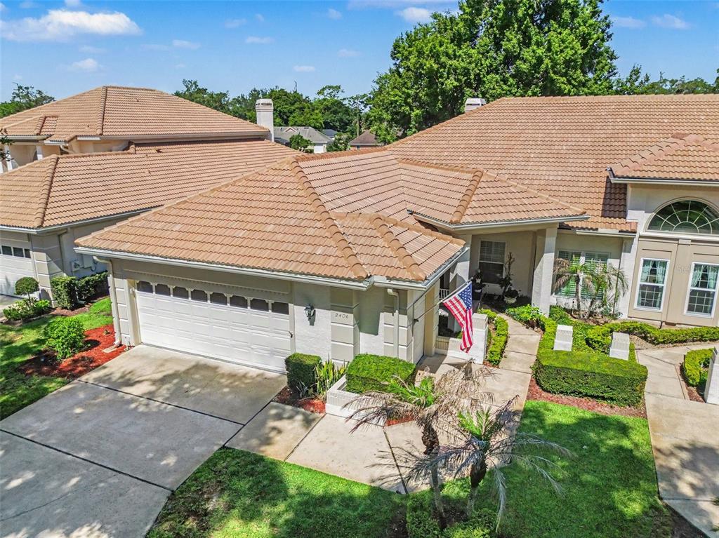 An aerial view shows a single-story house with a tile roof and a two-car garage — 2406 SWEETWATER COUNTRY CLUB DRIVE, APOPKA, FL