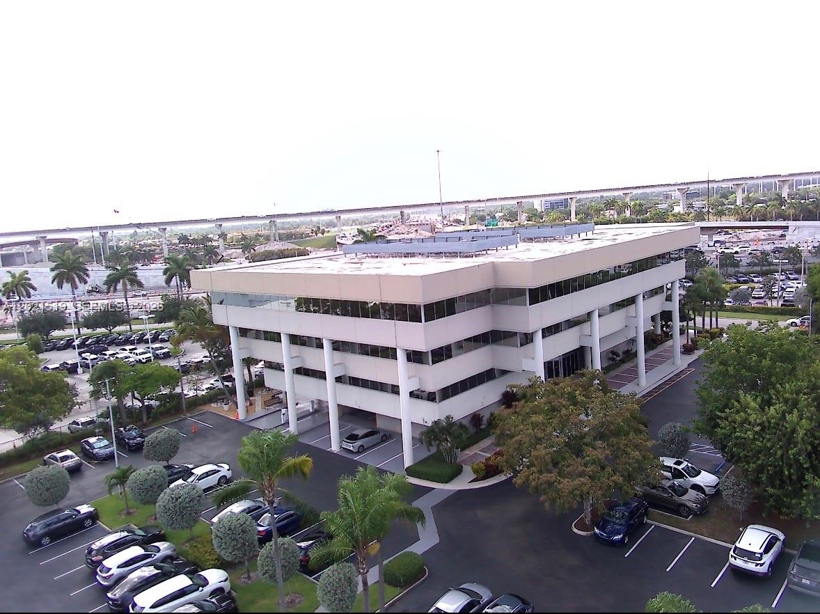 An aerial view shows a multi-story office building with a parking lot and highway overpass — 290 NW 165th St # 5B, Miami FL 33169, MIAMI, FL