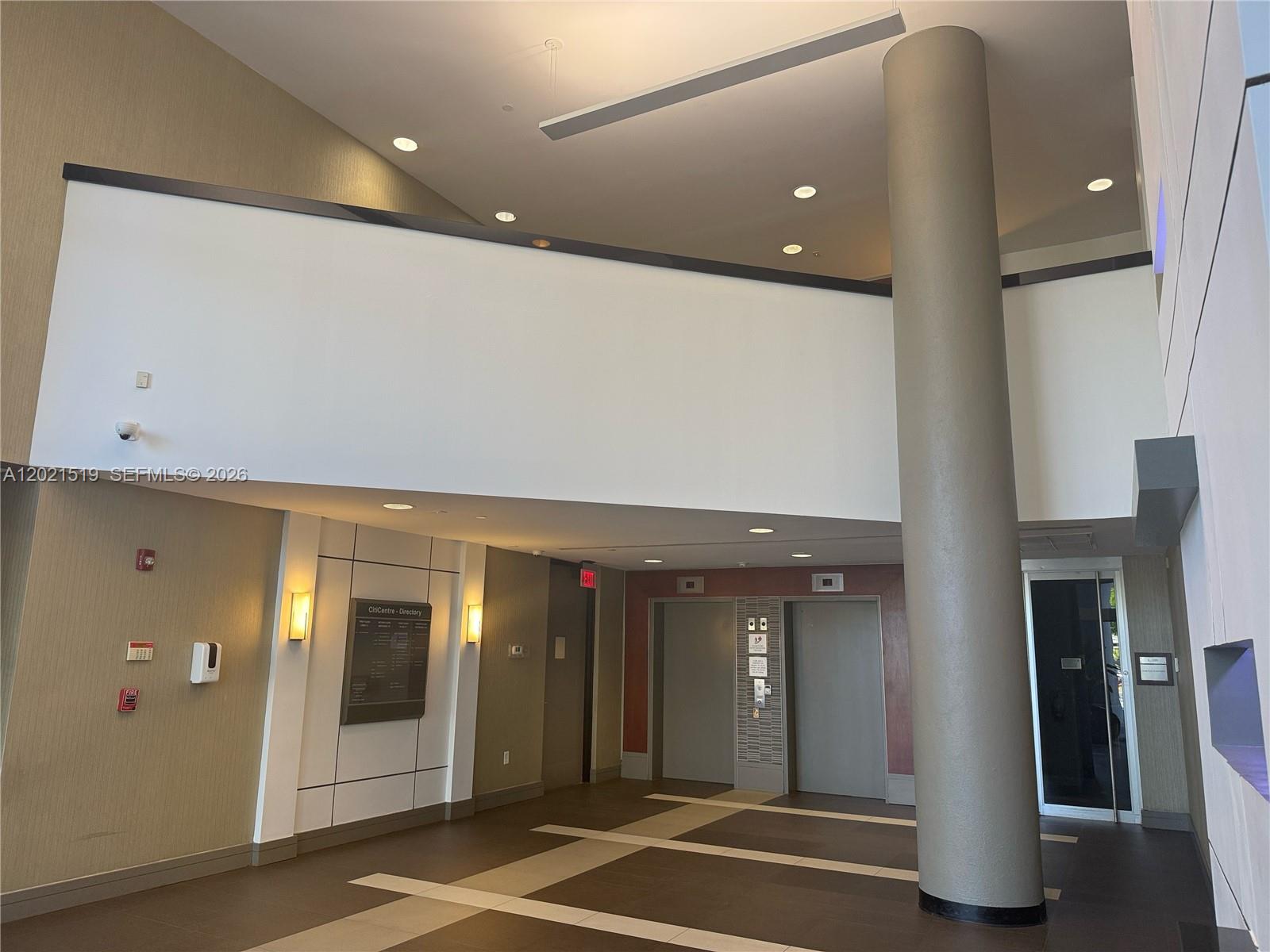 A modern building lobby features a large cylindrical column, elevator doors, and a directory sign — 290 NW 165th St # 5B, Miami FL 33169, MIAMI, FL