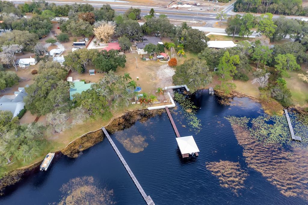 An aerial view shows a lakefront property with multiple docks, a boat, and surrounding trees — 5870 ALLIGATOR LAKE SHORE W, ST CLOUD, FL