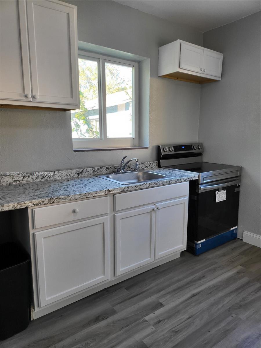 A kitchen features white cabinets, granite countertops, a stainless steel sink, and a black stove — 123 NW 59th St # C, Miami FL 33127, MIAMI, FL