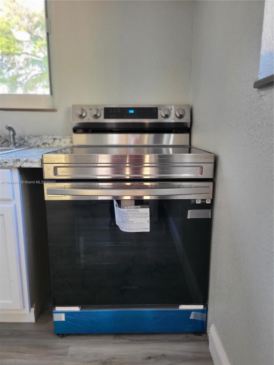 A stainless steel Samsung electric range is installed in a kitchen with granite countertops — 123 NW 59th St # C, Miami FL 33127, MIAMI, FL