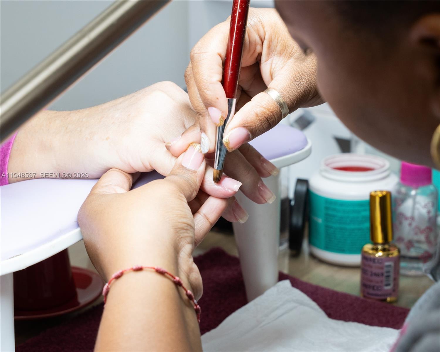 A manicurist applies acrylic to a client's fingernails at a salon workstation — 2452 W 60st, Hialeah FL 33016, HIALEAH, FL