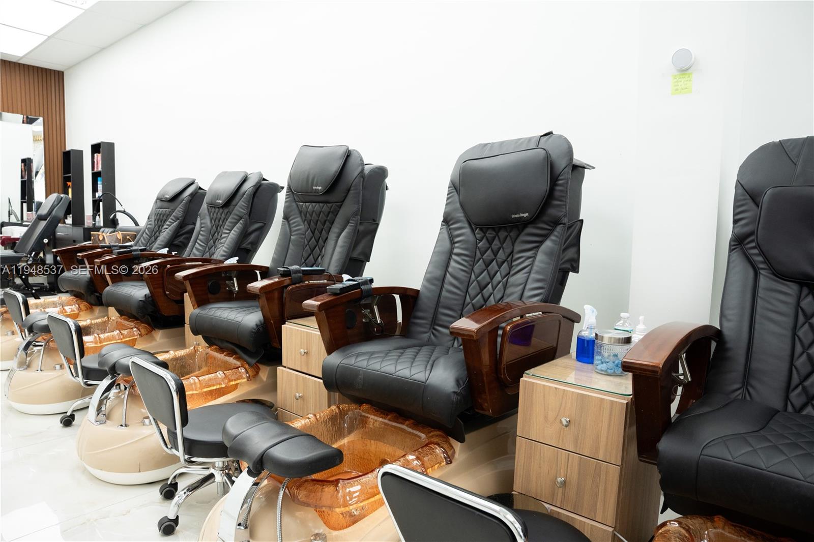 A row of black pedicure chairs with amber-colored foot basins sits in a salon — 2452 W 60st, Hialeah FL 33016, HIALEAH, FL