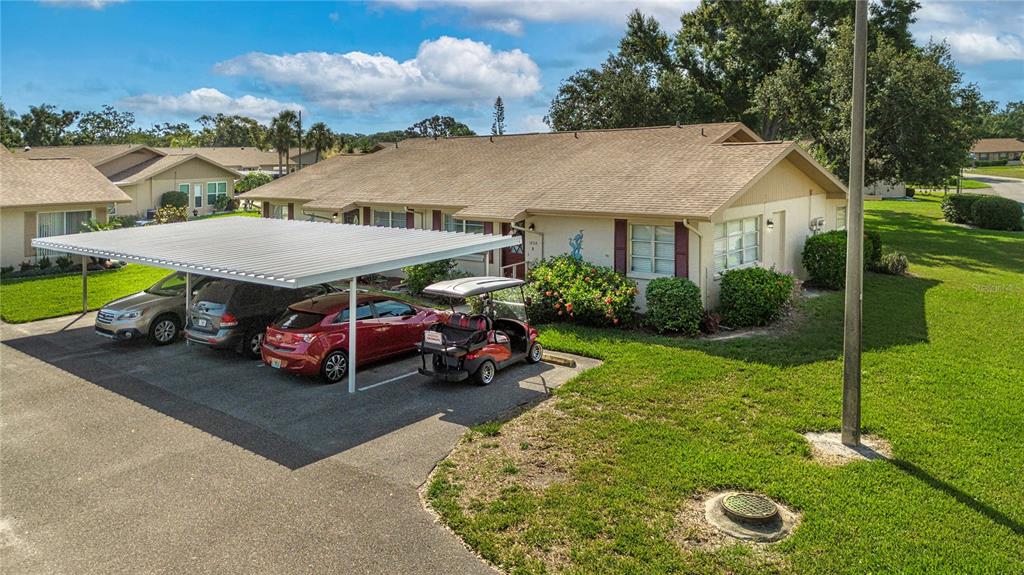A single-story residential building with a carport sheltering two cars and a golf cart — 1828 FOXHUNT DRIVE UNIT A, SUN CITY CENTER, FL