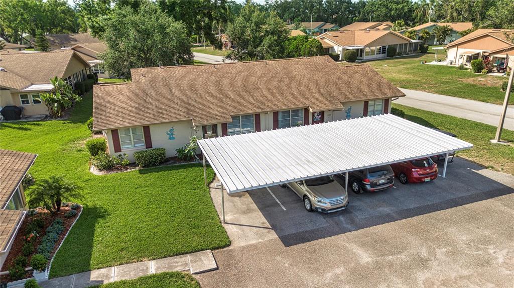 An aerial view of a single-story residential building with a large white metal carport — 1828 FOXHUNT DRIVE UNIT A, SUN CITY CENTER, FL