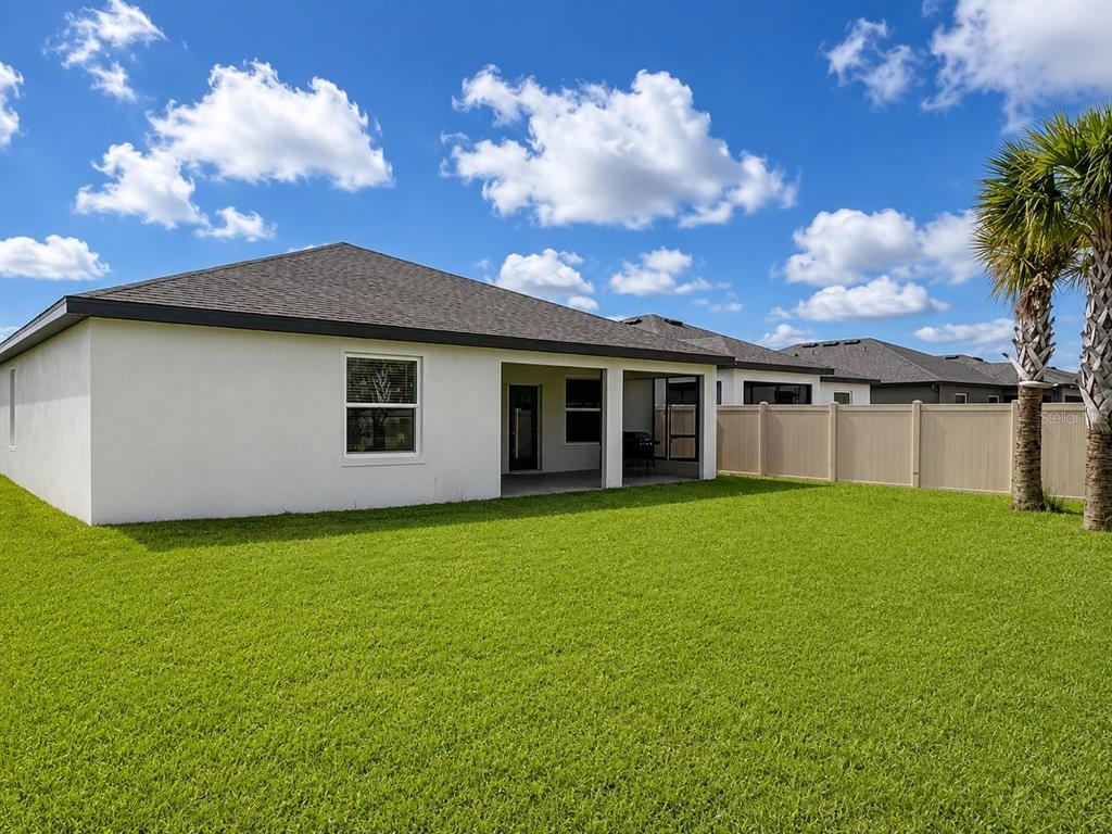 The exterior of a white house features a covered patio and a fenced backyard — 9706 LAST LIGHT GLEN, PARRISH, FL