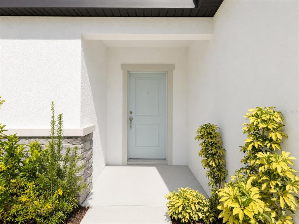 A light blue front door is set within a white stucco entryway with stone accents — 9706 LAST LIGHT GLEN, PARRISH, FL