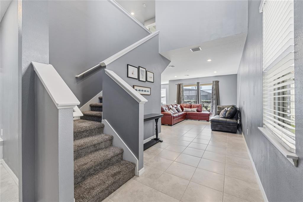 A living room features a grey sofa, a white armchair, and a television on a console — 5505 MISTY OAK CIRCLE, DAVENPORT, FL