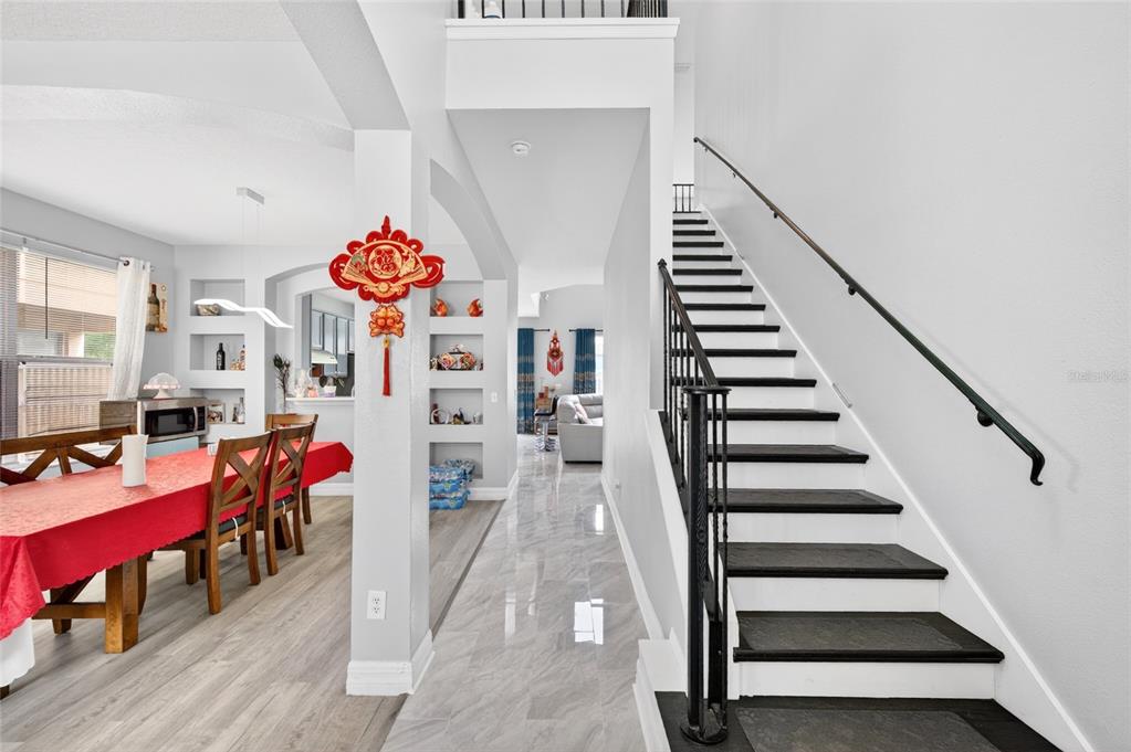 A dining area with a red tablecloth sits beside a staircase with black treads — 13538 HIDDEN FOREST CIRCLE, ORLANDO, FL