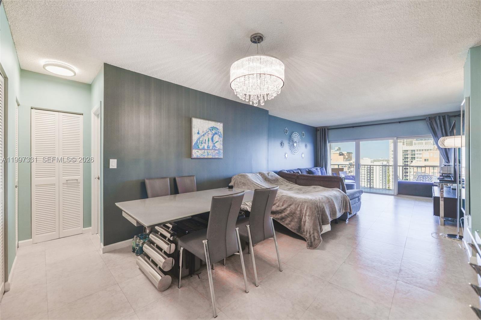 A dining area and living room feature a crystal chandelier, dark accent wall, and balcony — 1950 S Ocean Dr # 20D, Hallandale Beach FL 33009, HALLANDALE BEACH, FL