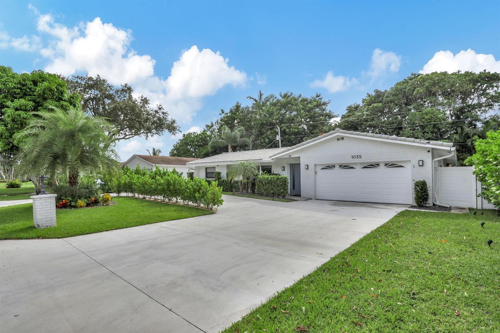 A white brick single-story house features a two-car garage and a concrete driveway — 1035 NW 5th Avenue, Boca Raton FL 33432, BOCA RATON, FL