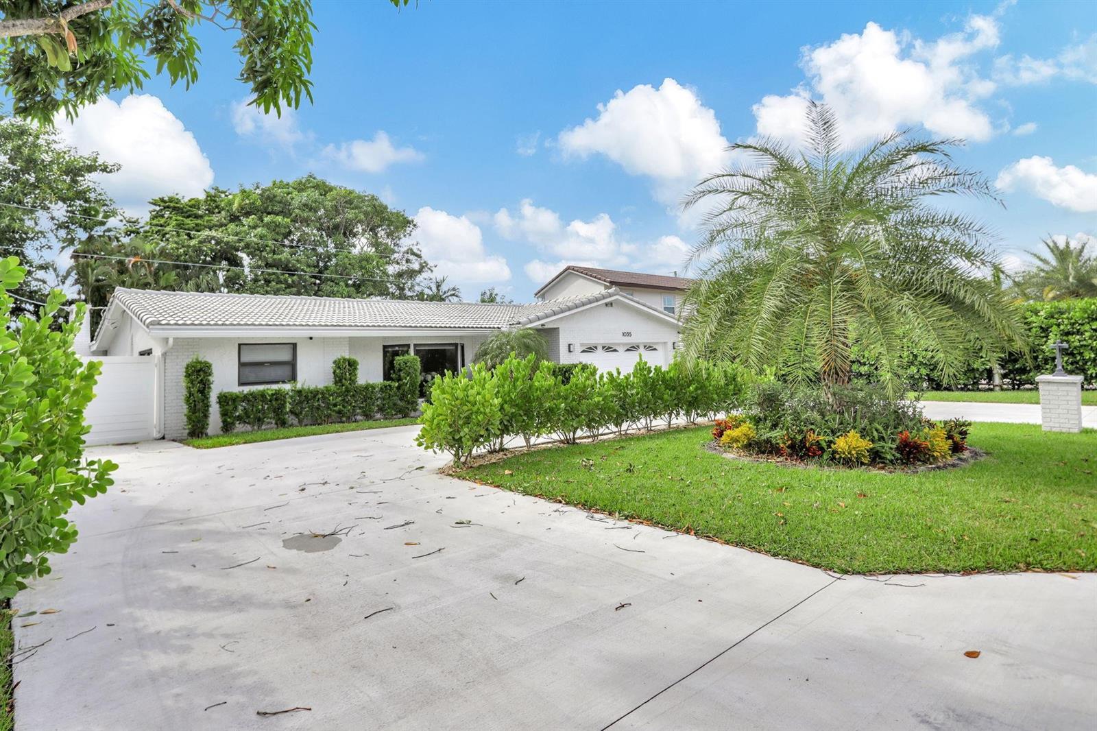 A white single-story house features a tile roof, a concrete driveway, and manicured landscaping — 1035 NW 5th Avenue, Boca Raton FL 33432, BOCA RATON, FL