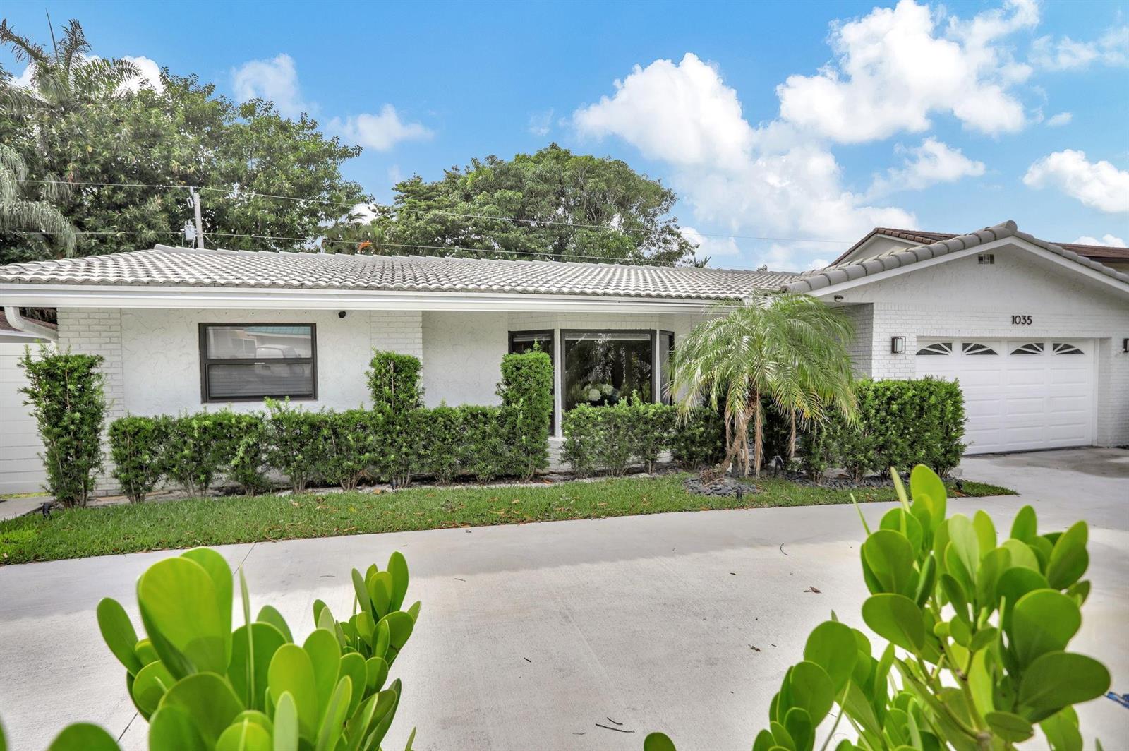 A white single-story house with a tiled roof, a garage, and manicured hedges in front — 1035 NW 5th Avenue, Boca Raton FL 33432, BOCA RATON, FL