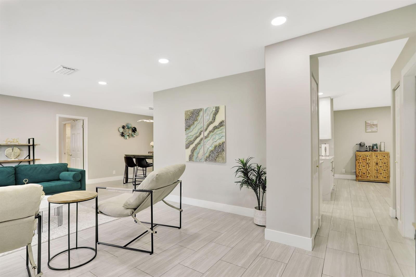 A modern living room features a teal sofa, neutral armchairs, and light wood-look tile flooring — 1035 NW 5th Avenue, Boca Raton FL 33432, BOCA RATON, FL
