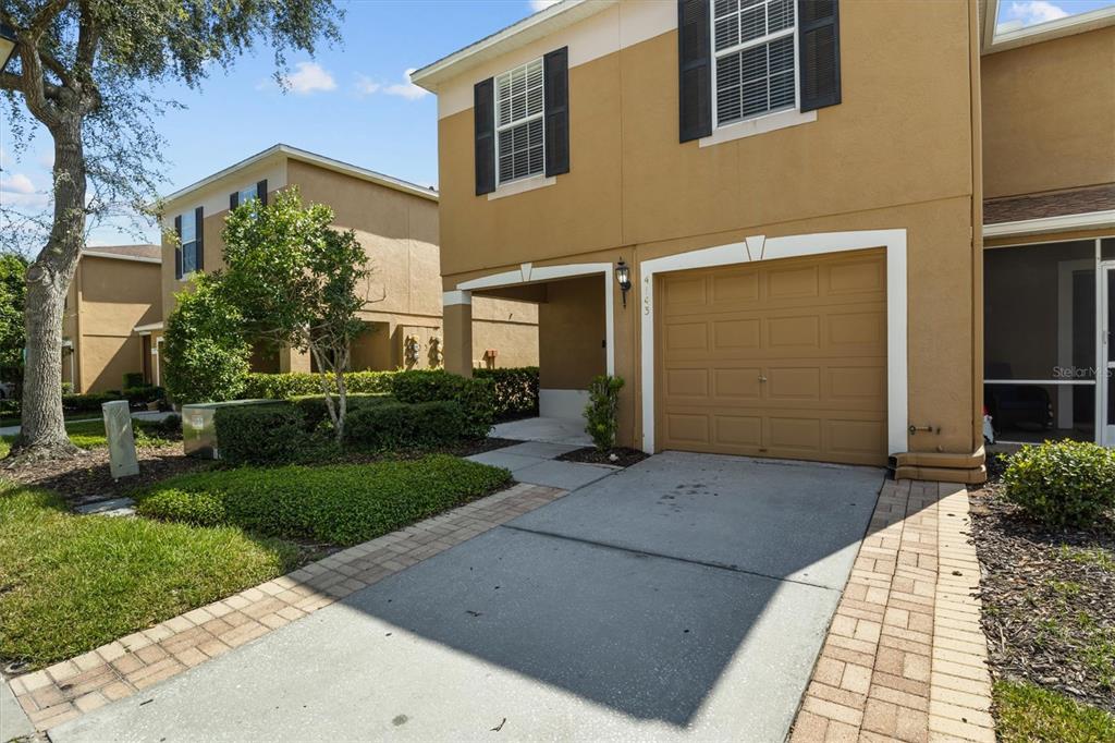A two-story tan townhouse features a single-car garage and a paved driveway — 4143 WINDING RIVER WAY, LAND O LAKES, FL