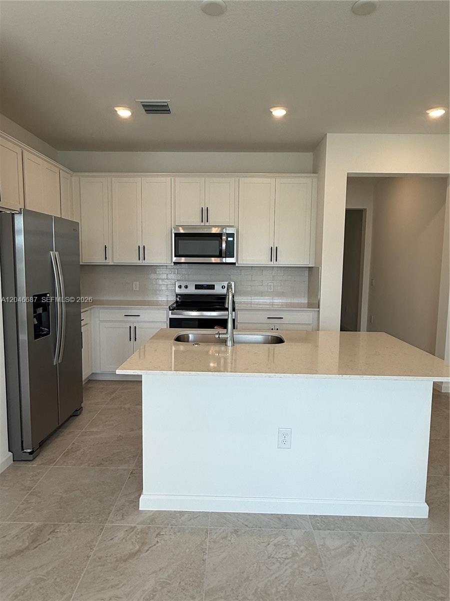 A kitchen features white cabinets, stainless steel appliances, a center island, and light-colored countertops — 4286 Efendi Drive, Lantana FL 33462, LANTANA, FL