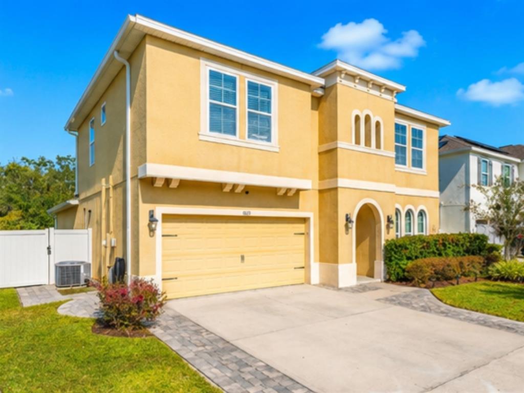 A two-story yellow stucco house with a two-car garage and a paved driveway — 1889 RUSTIC FALLS DRIVE, KISSIMMEE, FL