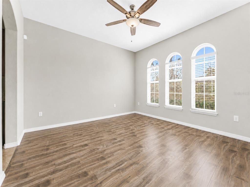 An empty room with wood-look flooring, a ceiling fan, and three arched windows — 1889 RUSTIC FALLS DRIVE, KISSIMMEE, FL