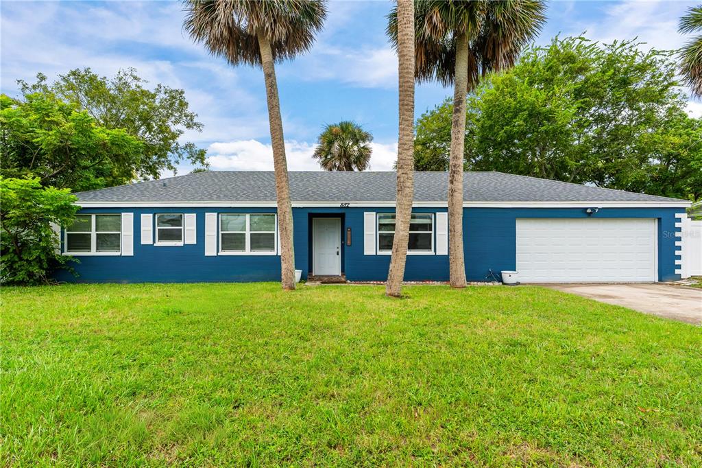 A single-story blue house with a white garage door and two palm trees in front — 882 W COQUINA DRIVE, DAYTONA BEACH, FL