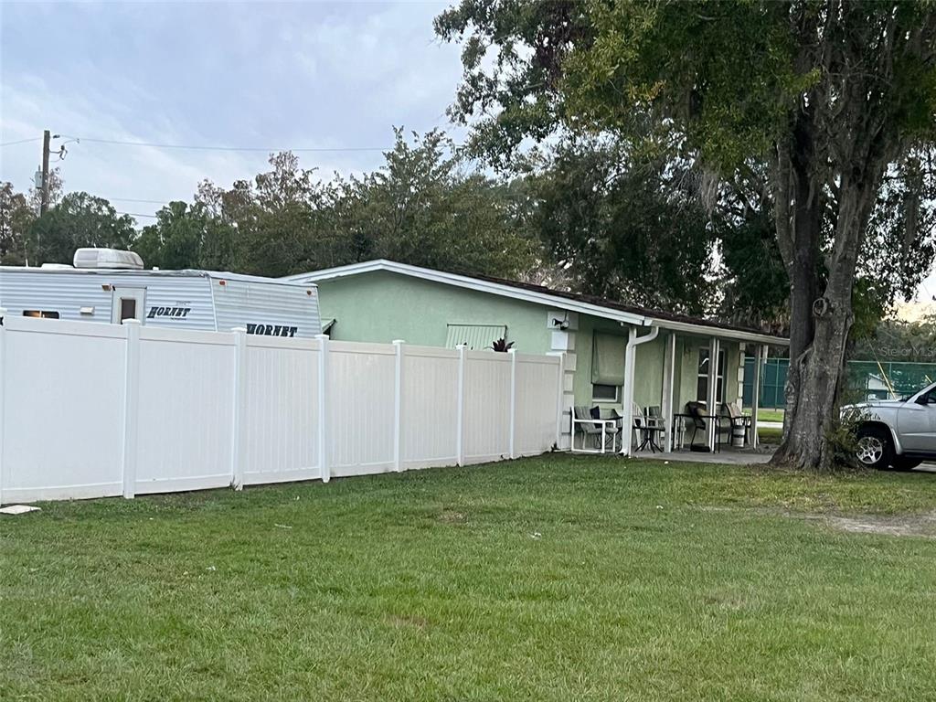 A light green house with a covered porch sits behind a white vinyl privacy fence — 1520 HILL STREET, KISSIMMEE, FL