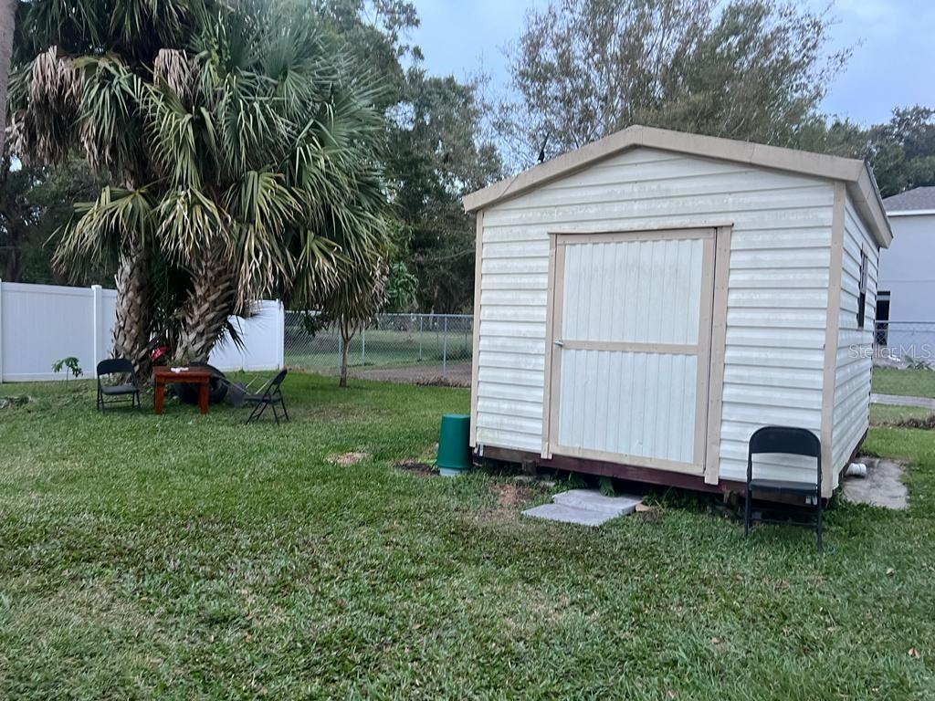 A backyard features a white storage shed, a palm tree, and several folding chairs — 1520 HILL STREET, KISSIMMEE, FL