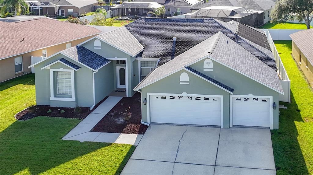 An aerial view of a single-story house with a three-car garage and shingled roof — 24807 BLAZING TRAIL WAY, LAND O LAKES, FL
