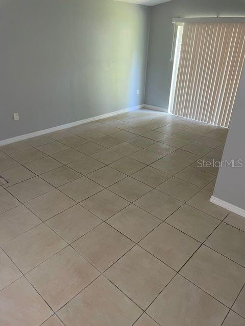 An empty room features light-colored floor tiles, gray walls, and vertical blinds over a door — 419 PINEAPPLE STREET UNIT 3, TARPON SPRINGS, FL
