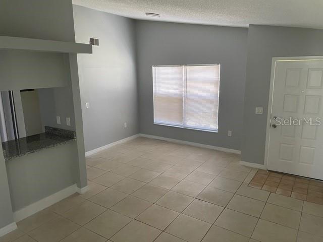 A living area with light gray walls, tile flooring, a window with blinds, and a doorway — 419 PINEAPPLE STREET UNIT 3, TARPON SPRINGS, FL
