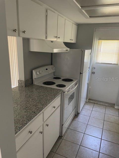 A kitchen featuring white cabinets, granite countertops, a white electric stove, and tile flooring — 419 PINEAPPLE STREET UNIT 3, TARPON SPRINGS, FL