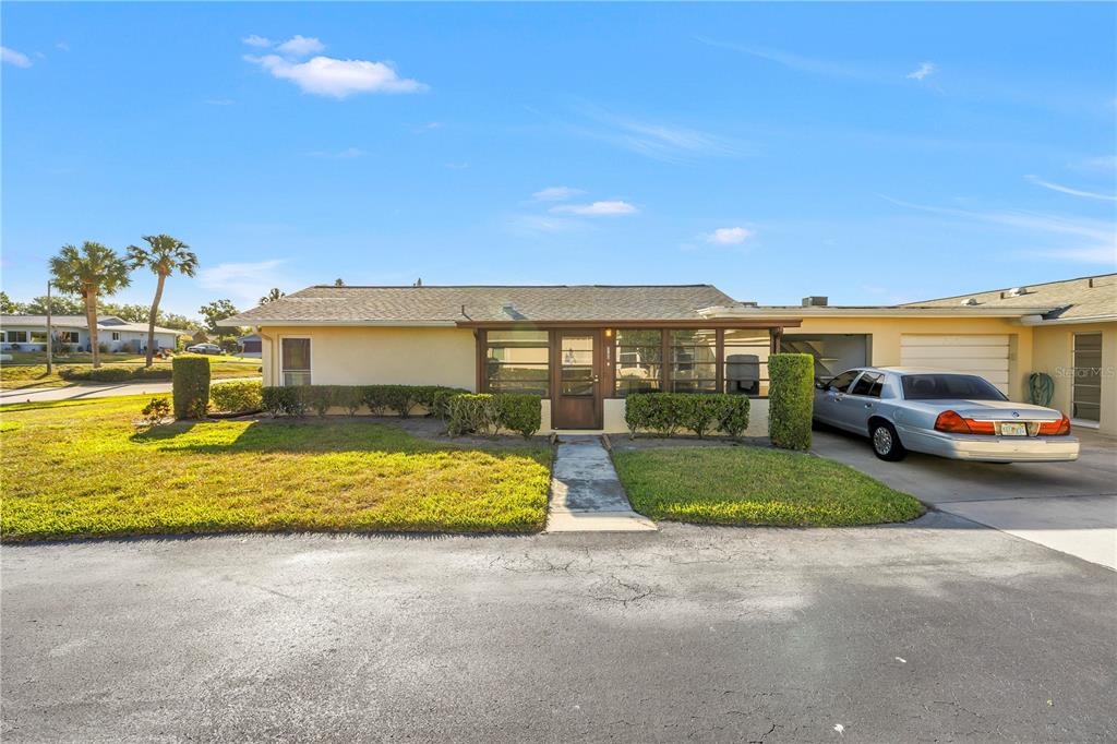 A single-story house with a screened front porch, a driveway, and a parked sedan — 2740 HIGHLANDS BOULEVARD UNIT B, PALM HARBOR, FL