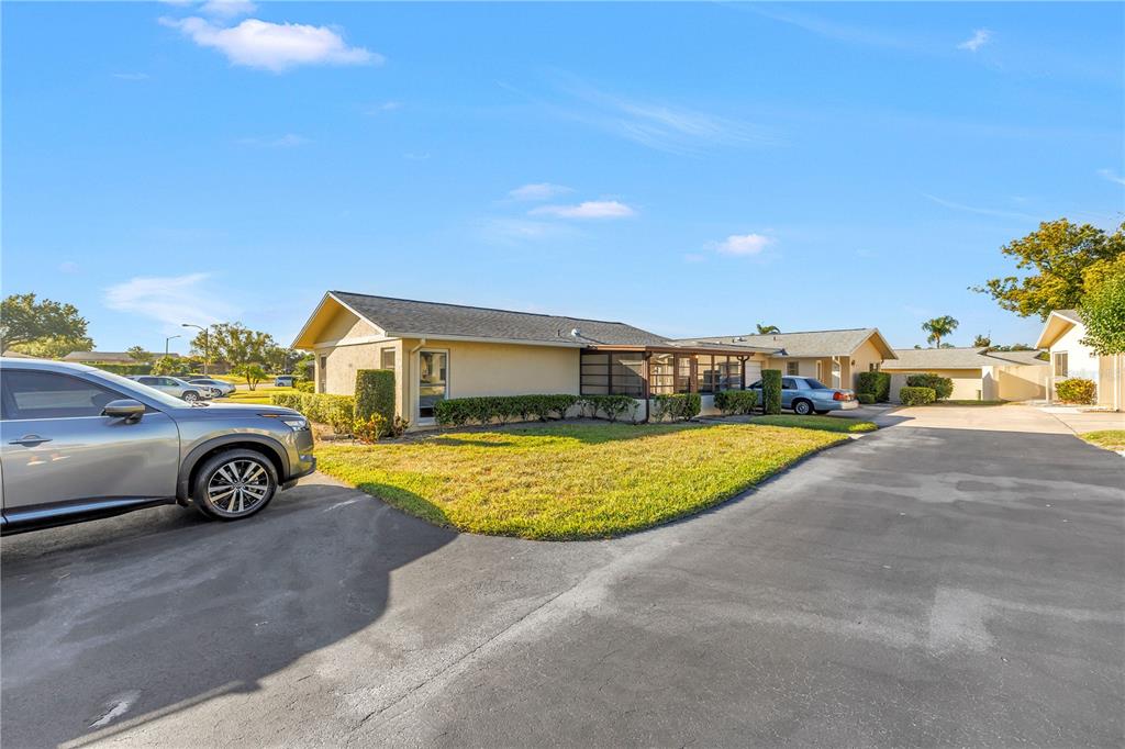 A tan single-story house with a screened porch sits next to a paved driveway — 2740 HIGHLANDS BOULEVARD UNIT B, PALM HARBOR, FL